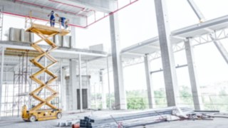 Plataforma tijera en una obra Operarios utilitzando una plataforma elevadora en una obra